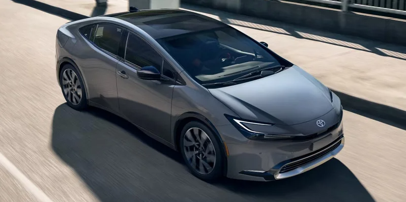 A silver 2025 Toyota Prius Plug-In Hybrid driving down the road.