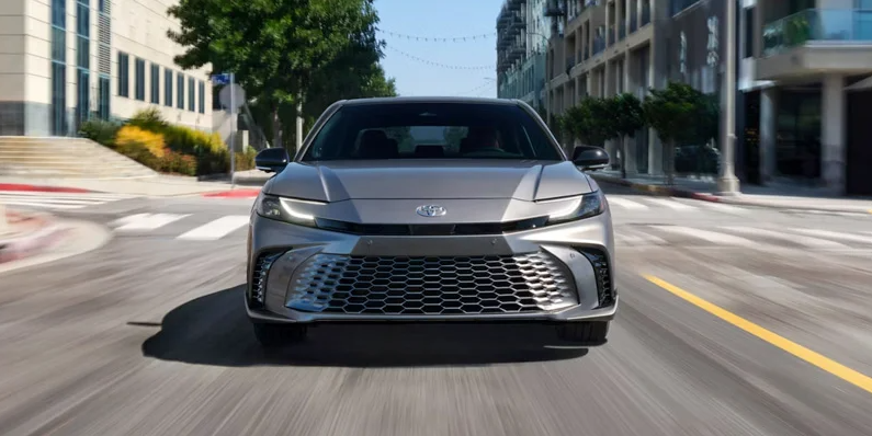 AA Silver 2026 Toyota Camry driving down the road.